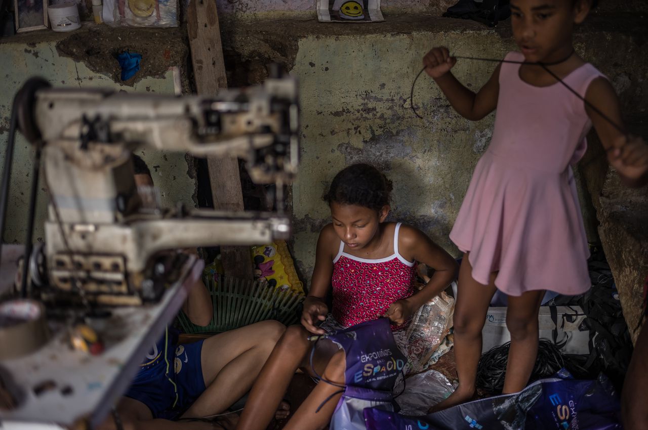 Een kind rijgt een veter door een plastic tasje als onderdeel van haar werk.