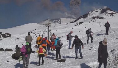 Toeristen skiën op vulkaan die as spuwt