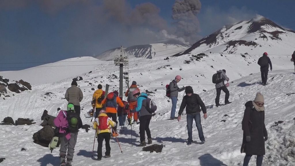 Toeristen skiën op vulkaan die as spuwt