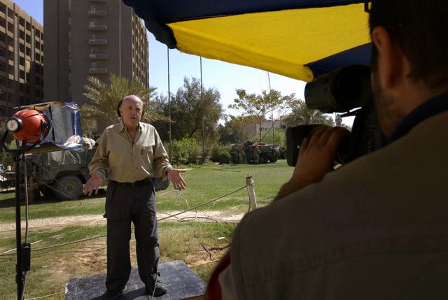 Peter Arnett, na zijn ontslag bij NBC, tijdens een ‘stand-upper’ in de tuin van het Palestine Hotel Bagdad in 2003.