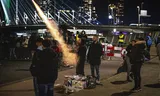 Vuurwerkliefhebbers steken, ondanks een verbod,  vuurwerk af bij de Erasmusbrug in Rotterdam op een eerdere Oudejaarsavond. 