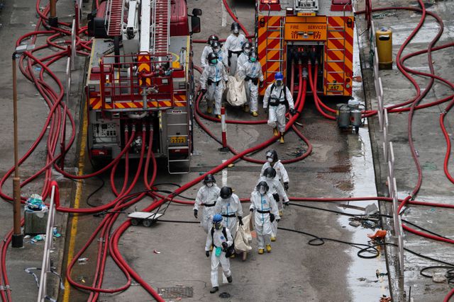 Politieagenten droegen zondag stoffelijke overschotten van slachtoffers uit het wooncomplex Wang Fuk Court in Hong Kong
