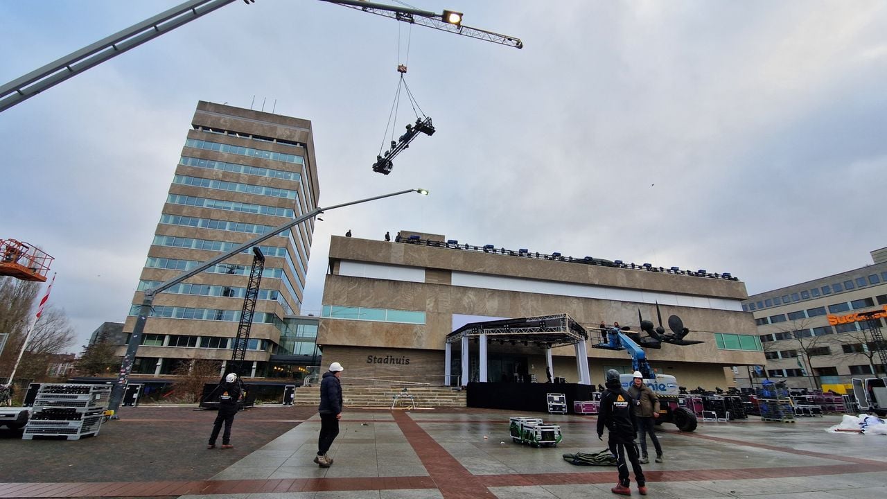 Met een grote kraan worden trussen met lampen op het dak van het stadhuis geplaatst