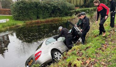 De wielrenners stabiliseren de in het water geraakte auto.