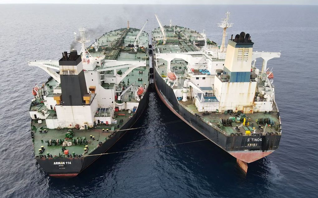 Twee olietankers in de kleuren groen, wit, zwart en rood, liggen naast elkaar op open zee. Ze zitten aan elkaar vast met kabels. 