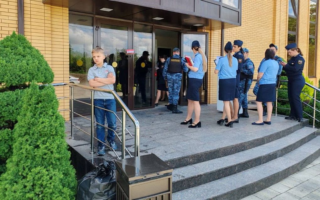 Politieagentes in uniform bij een groot, modern gebouw waarin een baptistengemeente samenkwam.