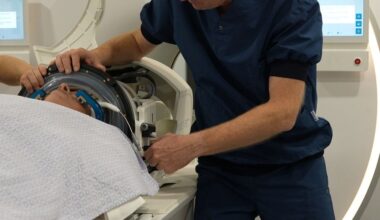 Een arts in blauwe kleding helpt een man die op een MRI-scanner ligt met een helm op zijn hoofd.