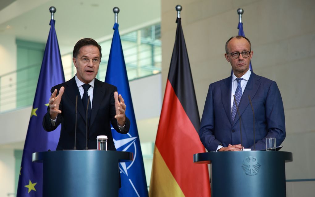 Twee heren in formele kleding achter spreekgestoelte.