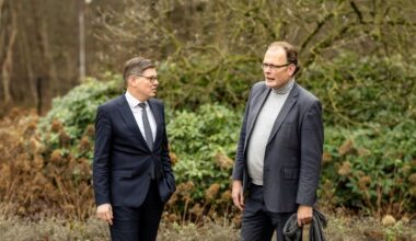 Twee mannen in gesprek. Op de achtergrond struikgewas.