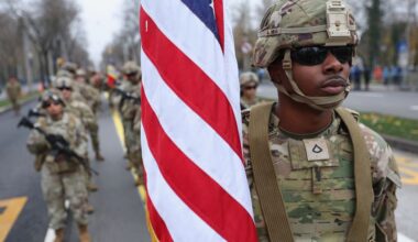 Amerikaanse soldaten in groene uniformen; de voorste draagt een vlag.