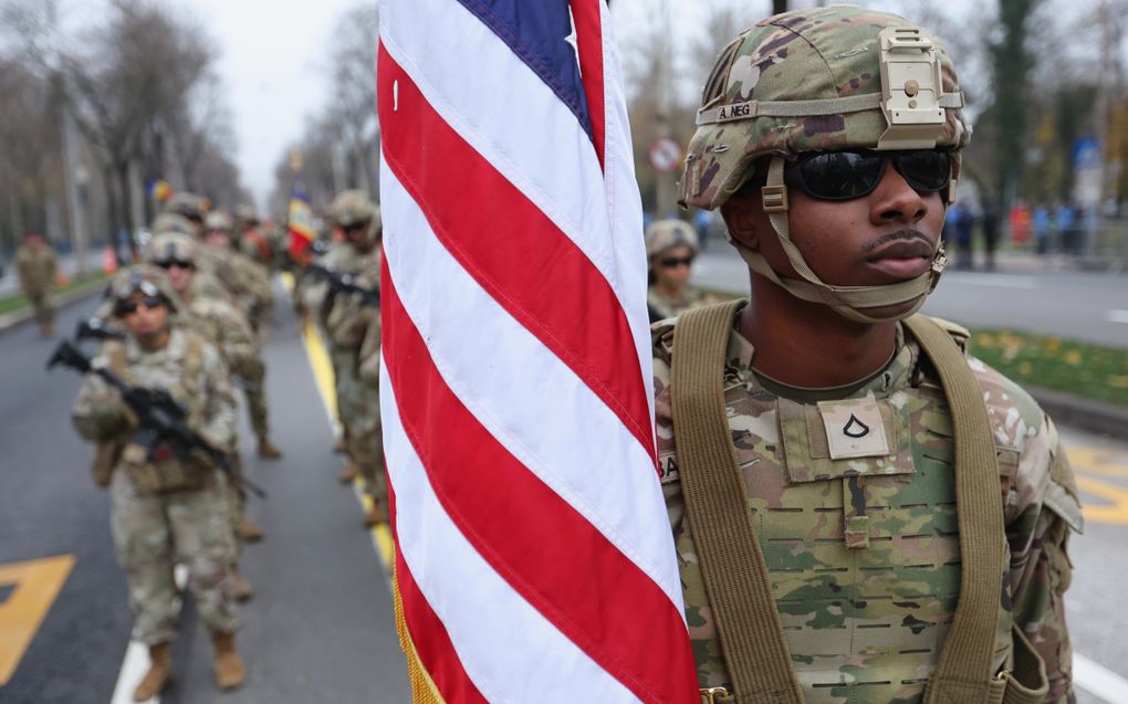 Amerikaanse soldaten in groene uniformen; de voorste draagt een vlag.