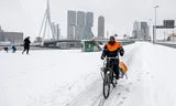 Fietsers in de sneeuw bij de erasmusbrug   tijdens sneeuwval. 