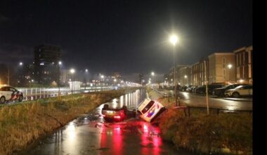 Het is glad! Politieauto die komt helpen glijdt ook zelf in het water