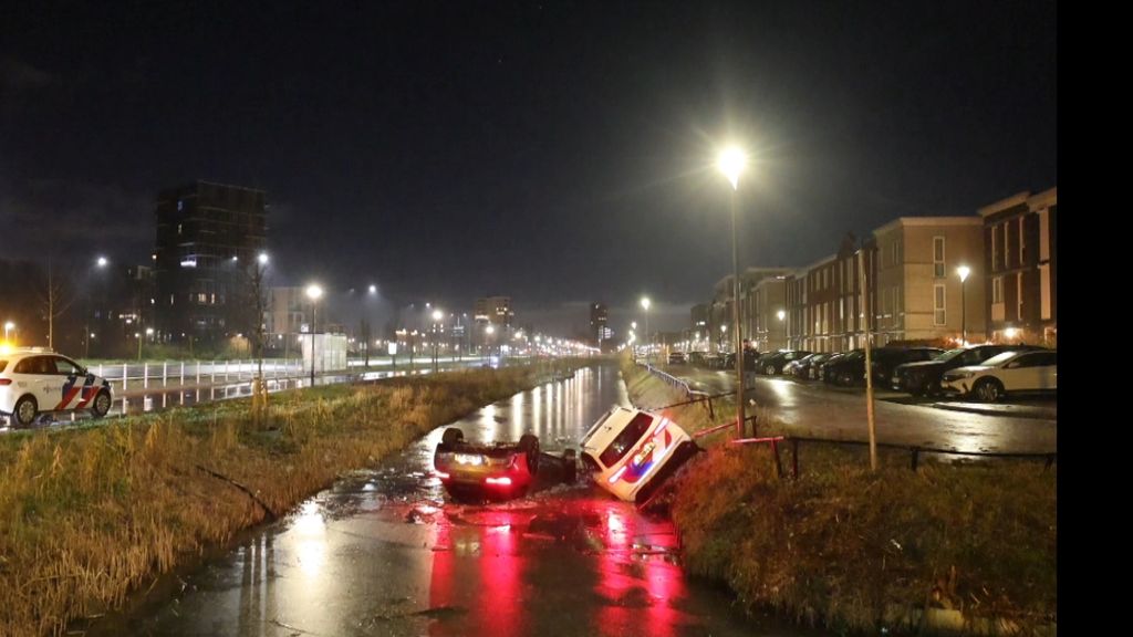 Het is glad! Politieauto die komt helpen glijdt ook zelf in het water