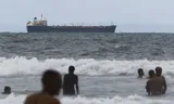 Venezolanen nemen een duik in de zee bij de kustplaats Puerto Cabello, met op de achtergrond de olietanker Evana. Die wordt gebruikt om olie te vervoeren tussen de binnenlandse havens in Venezuela.