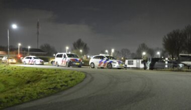 Meerdere politieauto's staan geparkeerd langs een weg in de nacht, met agenten bij een voertuig.