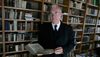 Man in pak in een studeerkamer met boeken.