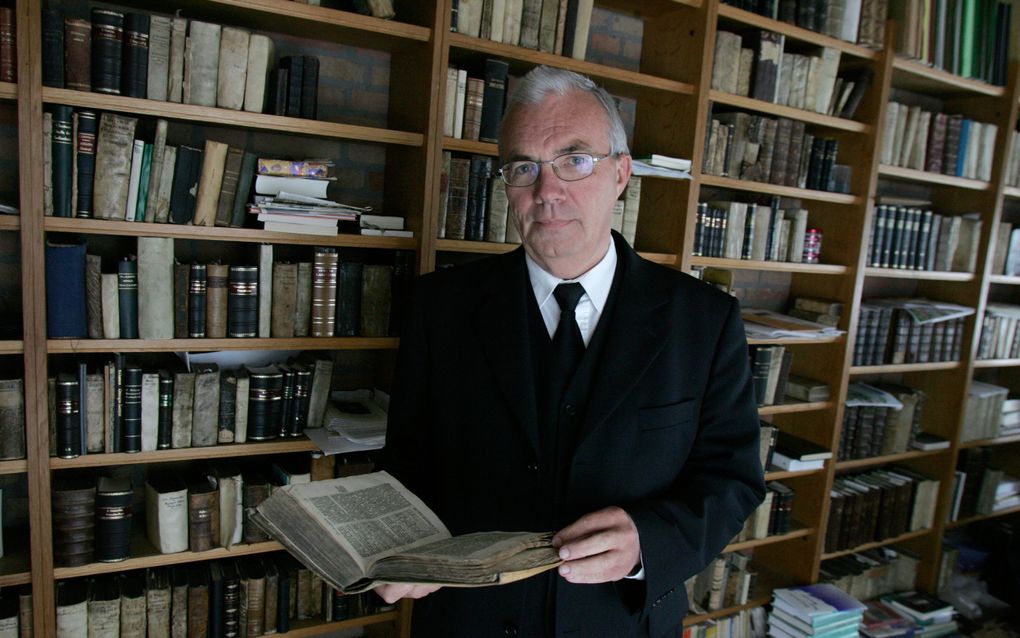 Man in pak in een studeerkamer met boeken.