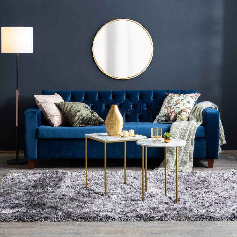 modern velvet sofa in a stylish living room with large round mirror and blue modern velvet sofa in a stylish living room with large round mirror and blue
