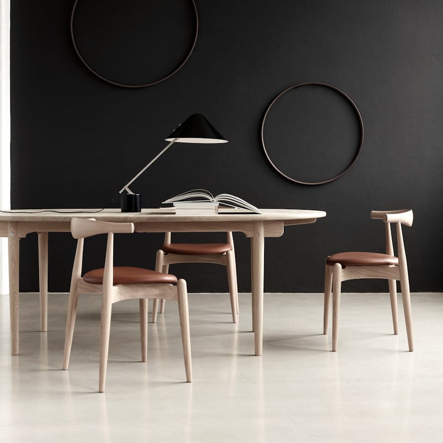 a modern dining area featuring a light wood table with two matching chairs and a black lamp a modern dining area featuring a light wood table with two matching chairs and a black lamp