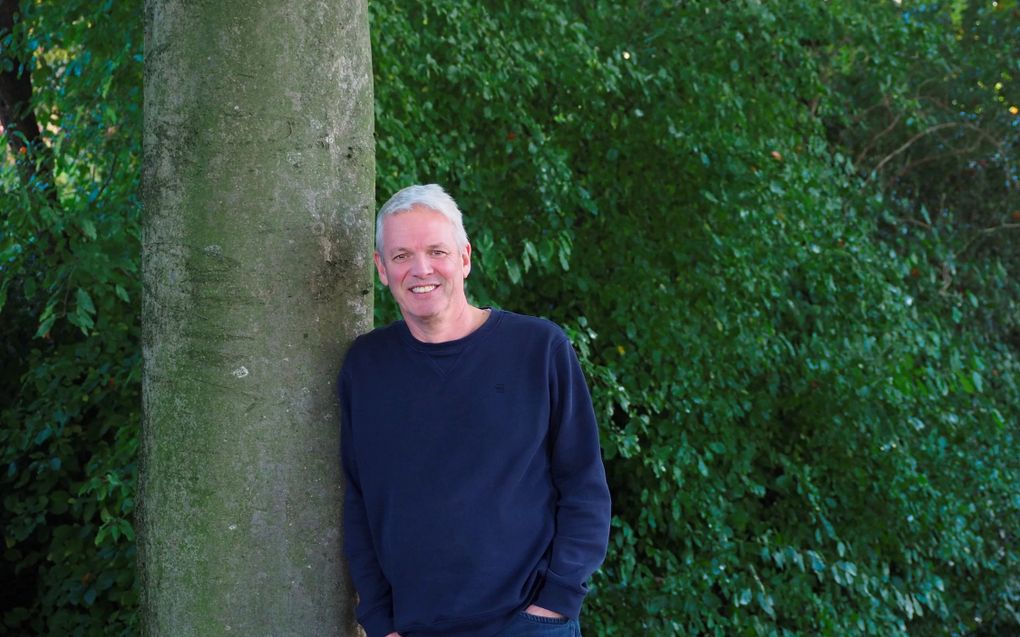 Portretfoto van een man met grijs haar en een donkerblauwe trui.