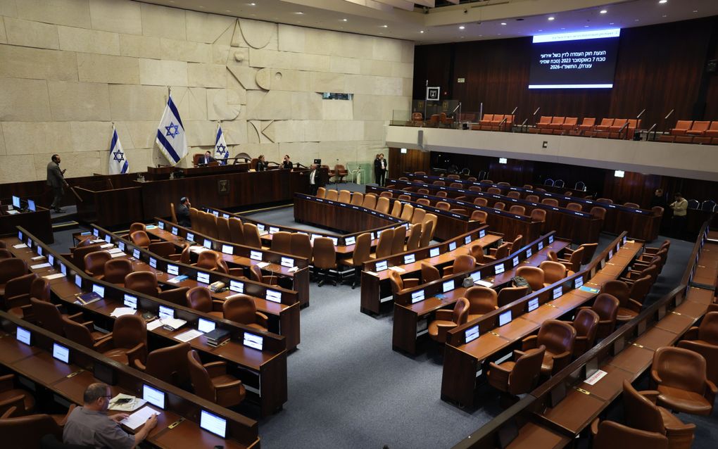Zo’n honderd bruine bankjes en tafels staan in een u-vorm. Op een verhoging zijn nog enkele stoelen, en daarachter staan drie Israëlische vlaggen.