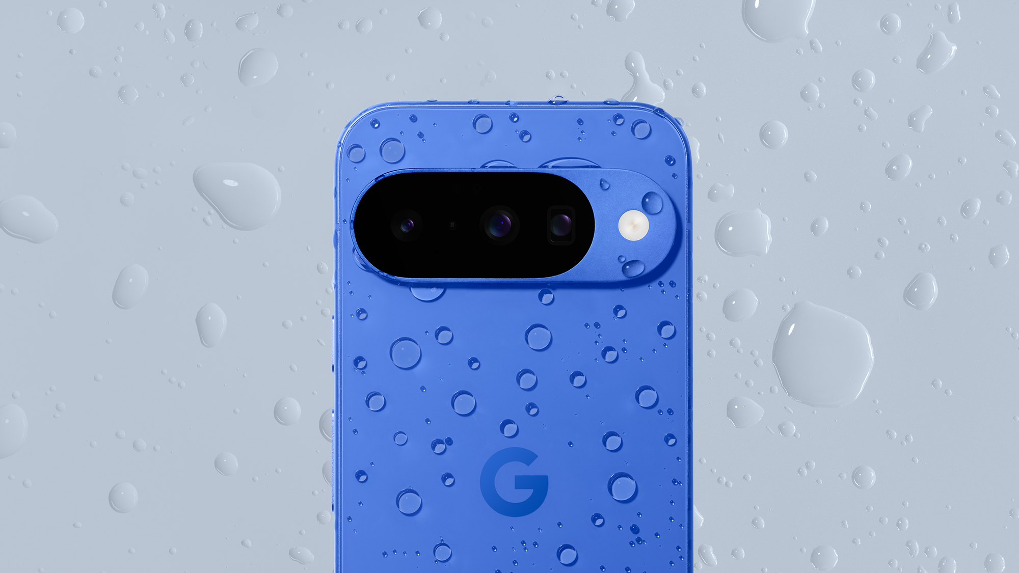 Google Pixel 10 i indigofarge dekket av vanndråper.