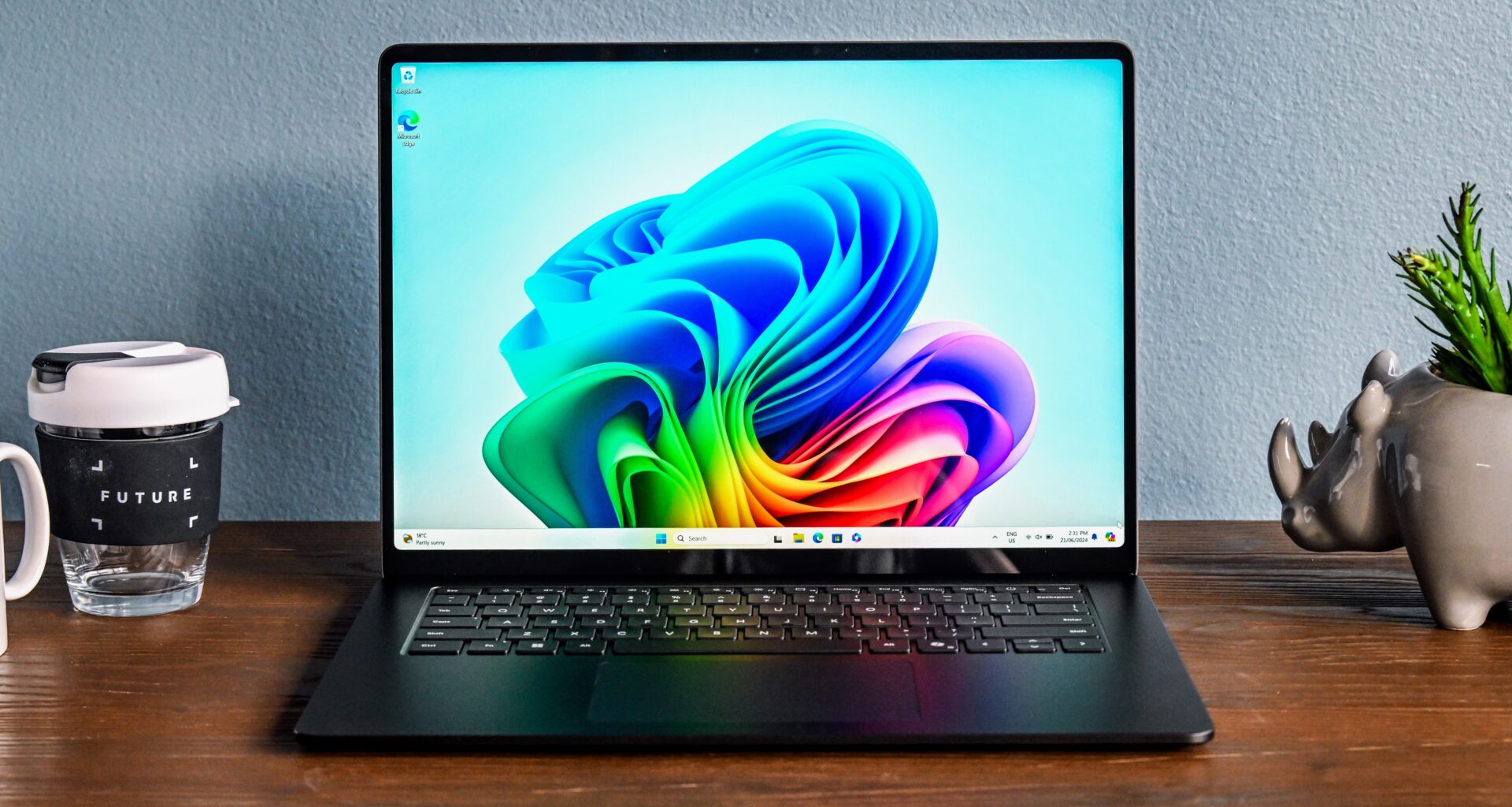 Microsoft Surface Laptop 7 på et trebord, sett forfra med åpen skjerm.