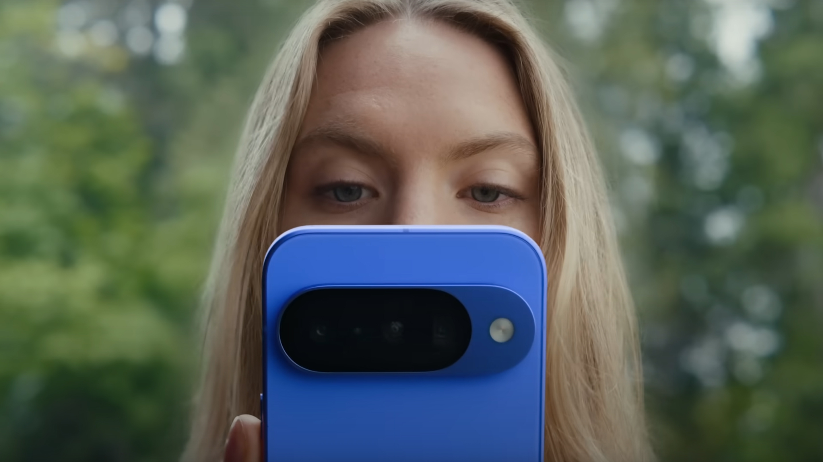 En kvinne som ser på en blå Google Pixel 10-telefon.