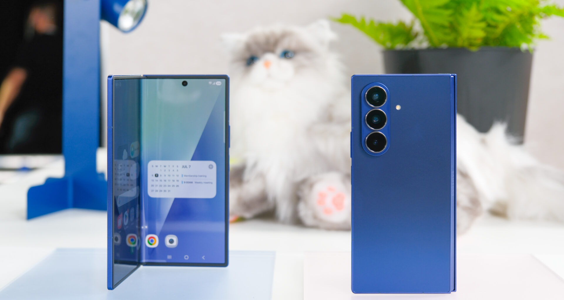 Two blue Samsung Galaxy Z Fold 7 devices with a stuffed cat behind them