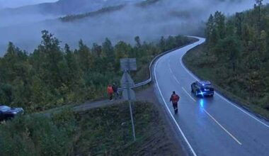 En sivil politibil står parkert på siden av veien mens en person kommer gående fra bilen.