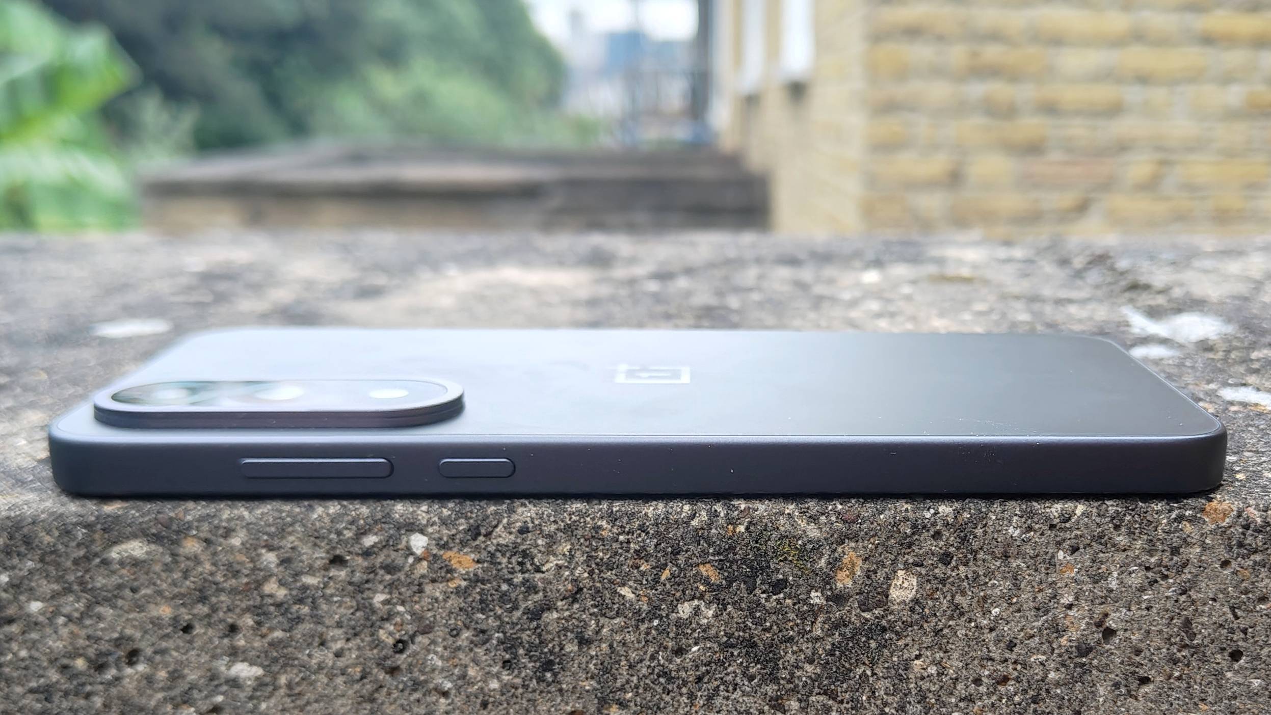 OnePlus Nord 5 ligger utend&oslash;rs p&aring; en murvegg.