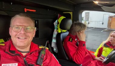 En mann i ambulanseuniform sitter inne i en ambulanse.