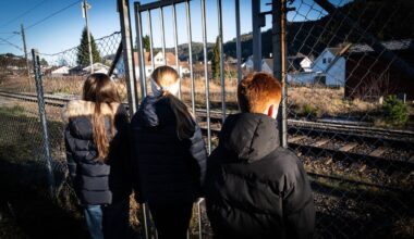 En gruppe barn som står utenfor noen togskinner.