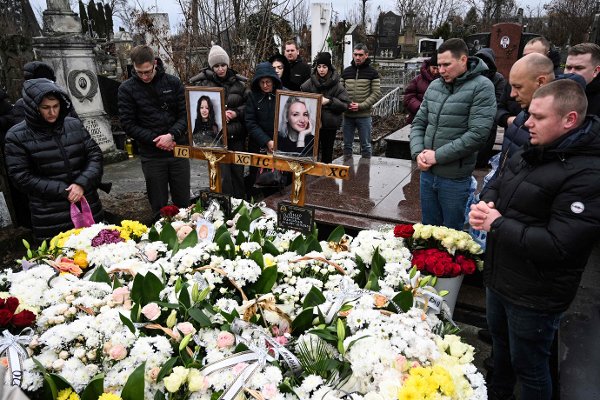 TOPSHOT - Relatives of 7-years-old Polish citizen Amelia Grzesko and her mother Oksana, killed in a missile attack on November 19, mourn by the graves during their funeral ceremony in Ternopil, on November 22, 2025, amid the Russian invasion of Ukraine. The death toll in the western city of Ternopil rose to 32, regional police said, after cruise missiles slammed into apartment blocks. The Ternopil attack came as Russia batters Ukraine's energy grid ahead of winter, and with Kyiv's stretched troops under pressure on the front line. (Photo by YURIY DYACHYSHYN / AFP)