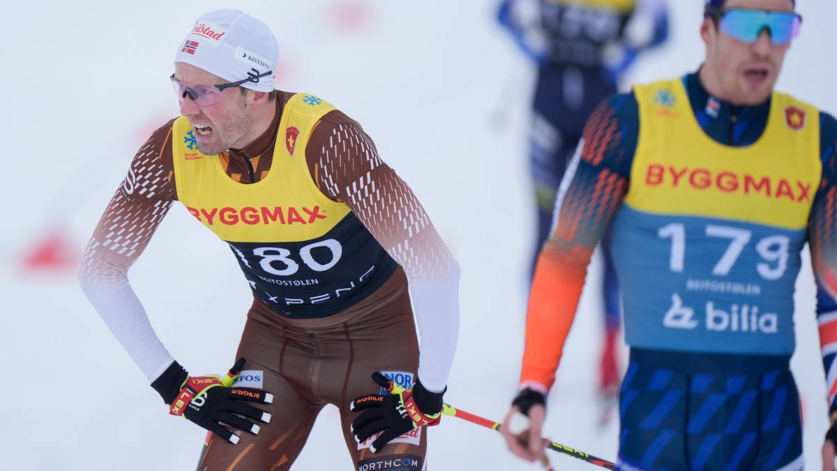 To personer i skiklær står på snøen. Den ene personen, iført en gul startnummertrøye med nummer 180, bøyer seg fremover og ser ut til å ta seg en pause. Den andre personen, med startnummer 179, står i bakgrunnen og ser mot konkurransen. Omgivelsene er preget av snødekte bakker og skistaver.