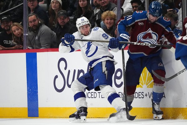 Tampa Bay Lightning defenseman J.J. Moser, left, struggles to control the puck with Colorado Avalanche center Brock Nelson in the third period of an NHL hockey game Tuesday, Nov. 4, 2025, in Denver. (AP Photo/David Zalubowski)