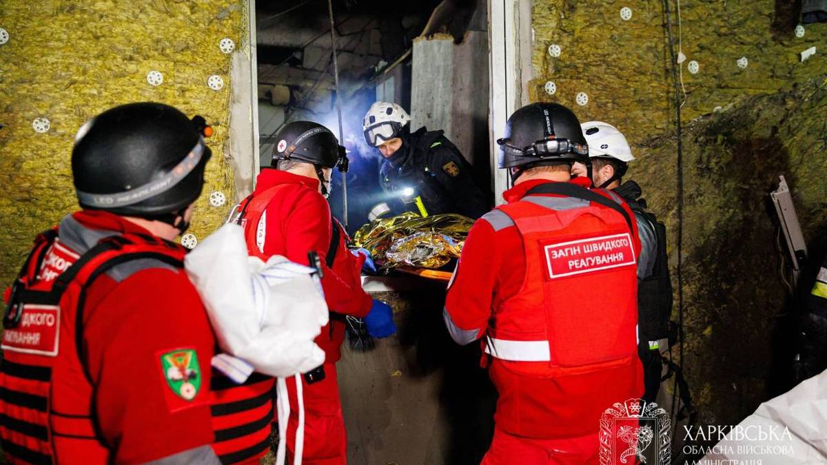 Redningspersoner bærer en person ut fra et hus som er truffet av russisk drone i byen Kharkiv