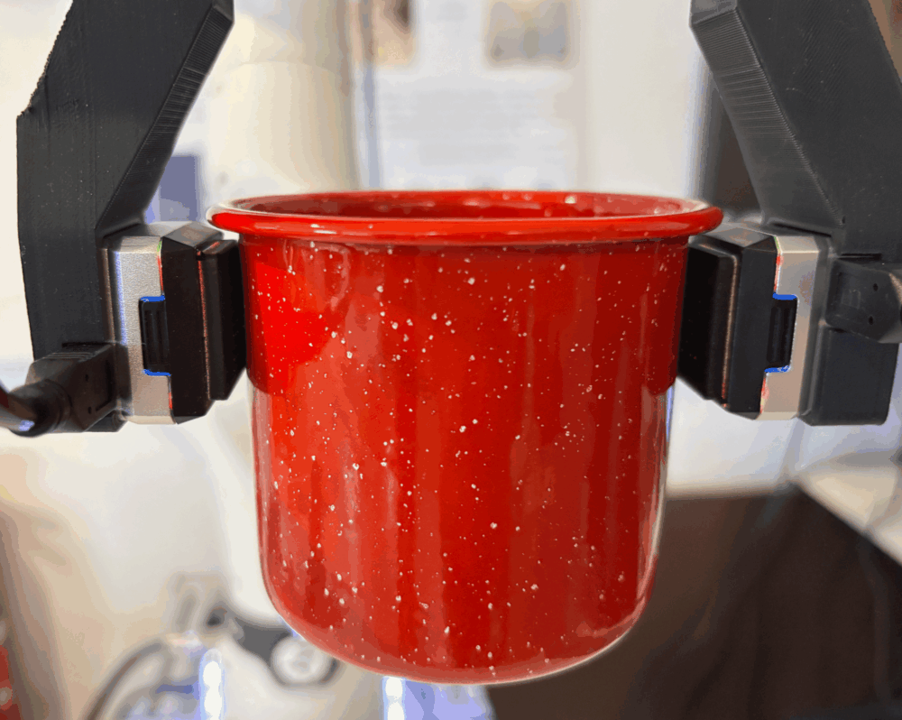 Robotfingre med gripeegenskaper holder en glatt kopp med vann.