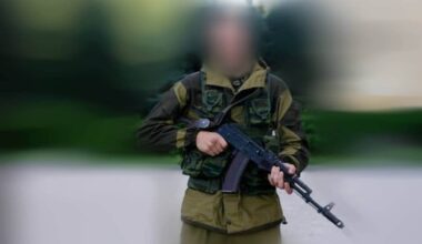 en mann med våpen ser i kamera