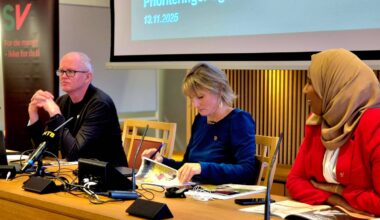 tre mennesker sitter bak et bord