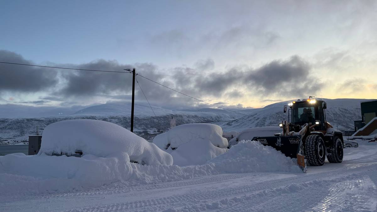 Bilene er dekt i snø i Tromsø, og en traktor brøyter ved siden av.