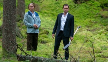 To menn står i skogen. Den ene har en spade i hånden.