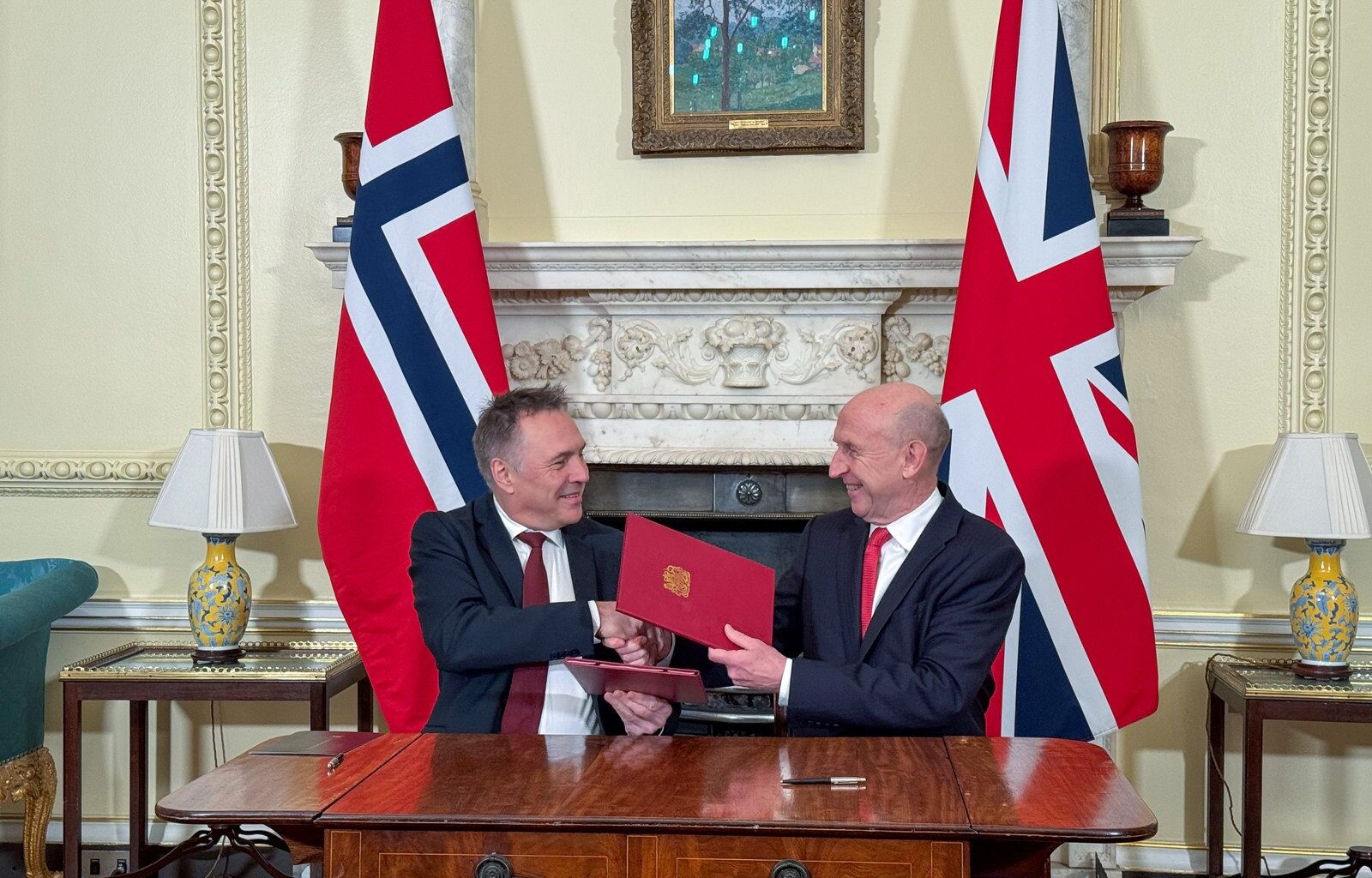 Nores og Storbritannias forsvarsministre tar hverandre i hendene etter avtalesignering.