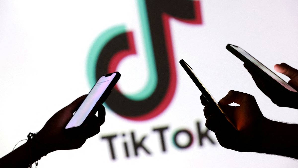 Flere hender holder mobiltelefoner foran en stor TikTok-logo på en lys bakgrunn.