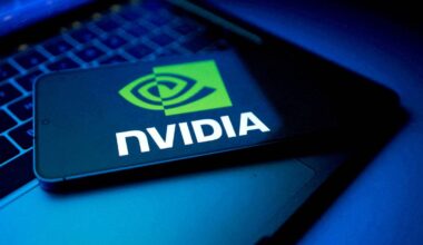 Et mobiltelefon med Nvidia-logoen ligger på et datamaskintastatur. Bakgrunnen er svakt belyst i blåaktige toner. Bildefokuset er på telefonen og logoen. Det er ingen personer tilstede. (Bildebeskrivelsen er laget av en KI-tjeneste)