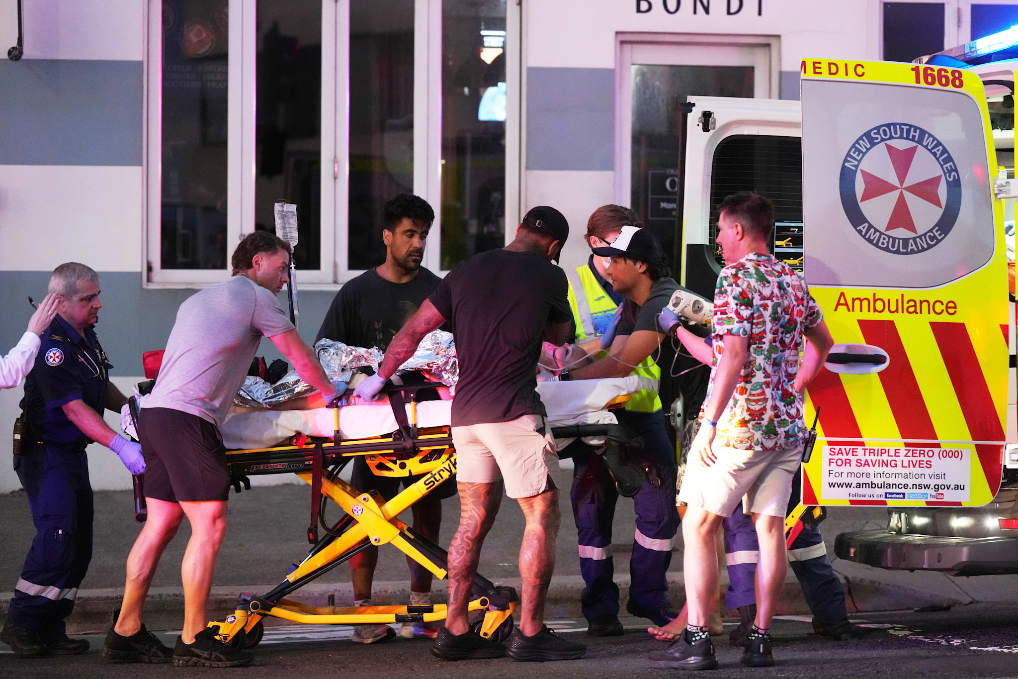 En person fraktes på båre inn i en ambulanse ved Bondi Beach etter skytingen i Sydney søndag. 