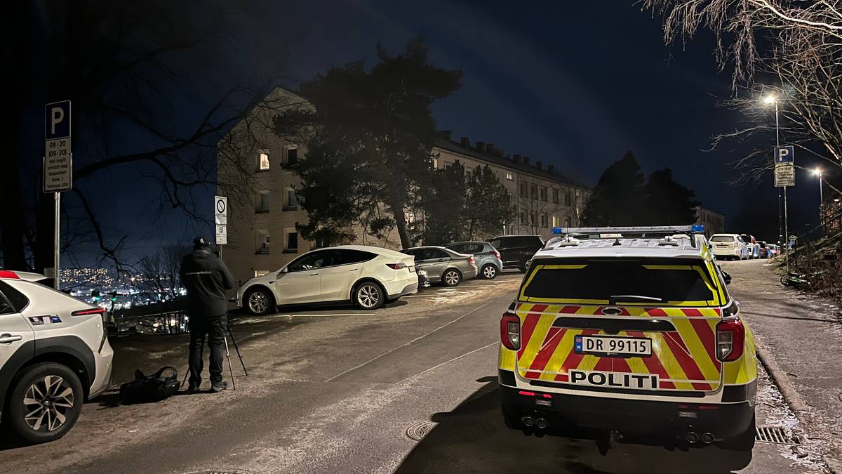 En politibil står parkert ved en kriminalteknikker i en gate om kvelden, i Oslo.