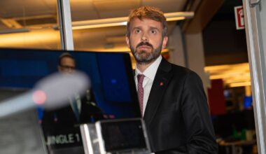 en mann i dress som holder en bærbar datamaskin