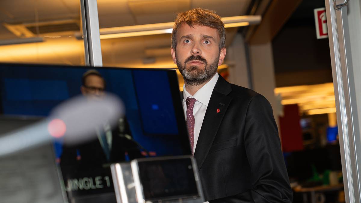 en mann i dress som holder en bærbar datamaskin